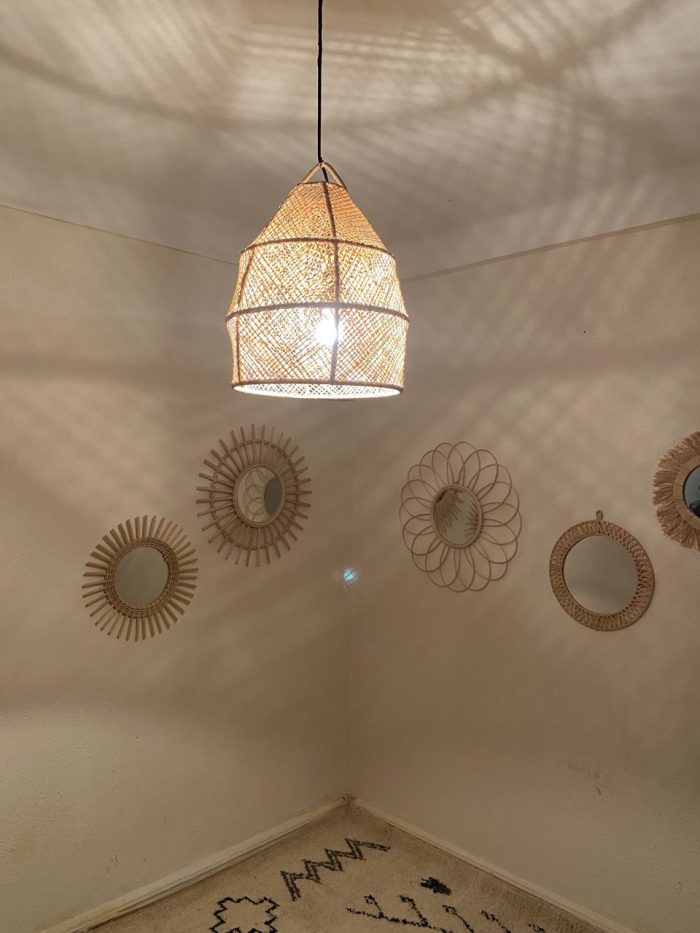 Handwoven raffia lantern pendant with tall tapered shape, natural woven raffia and structured metal frame.