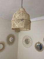 Handwoven raffia lantern pendant with tall tapered shape, natural woven raffia and structured metal frame.