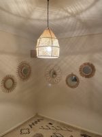 Handwoven raffia lantern pendant with tall tapered shape, natural woven raffia and structured metal frame.