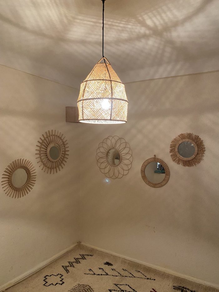 Handwoven raffia lantern pendant with tall tapered shape, natural woven raffia and structured metal frame.