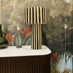 Black and natural raffia table lamp with vertical striped design, tall cylindrical base and wide handwoven drum lampshade.