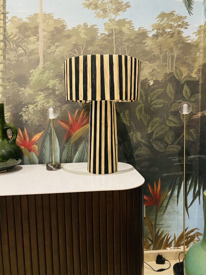 Black and natural raffia table lamp with vertical striped design, tall cylindrical base and wide handwoven drum lampshade.
