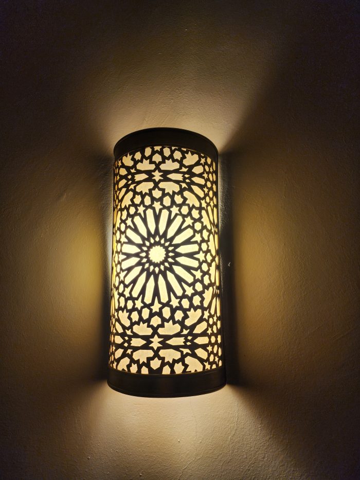 Handmade Moroccan rosette brass wall sconce with pierced floral pattern and warm ambient lighting.