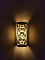 Handmade Moroccan rosette brass wall sconce with pierced floral pattern and warm ambient lighting.