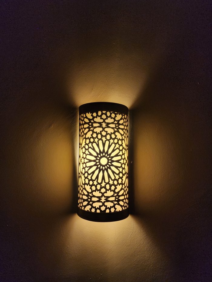 Handmade Moroccan rosette brass wall sconce with pierced floral pattern and warm ambient lighting.