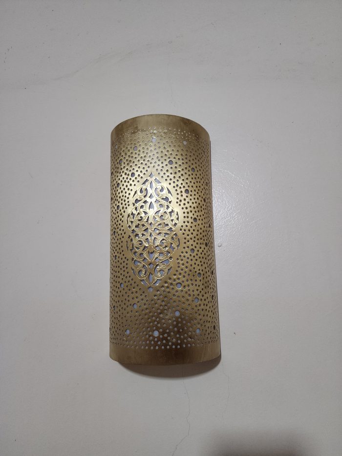 Handmade Moroccan pierced brass wall lamp with perforated pattern and warm up and down lighting.