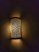 Handmade filigree brass wall sconce with intricate floral cutout pattern and warm ambient wall lighting.