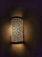 Handmade filigree brass wall sconce with intricate floral cutout pattern and warm ambient wall lighting.