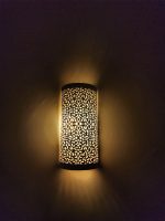 Handmade filigree brass wall sconce with intricate floral cutout pattern and warm ambient wall lighting.