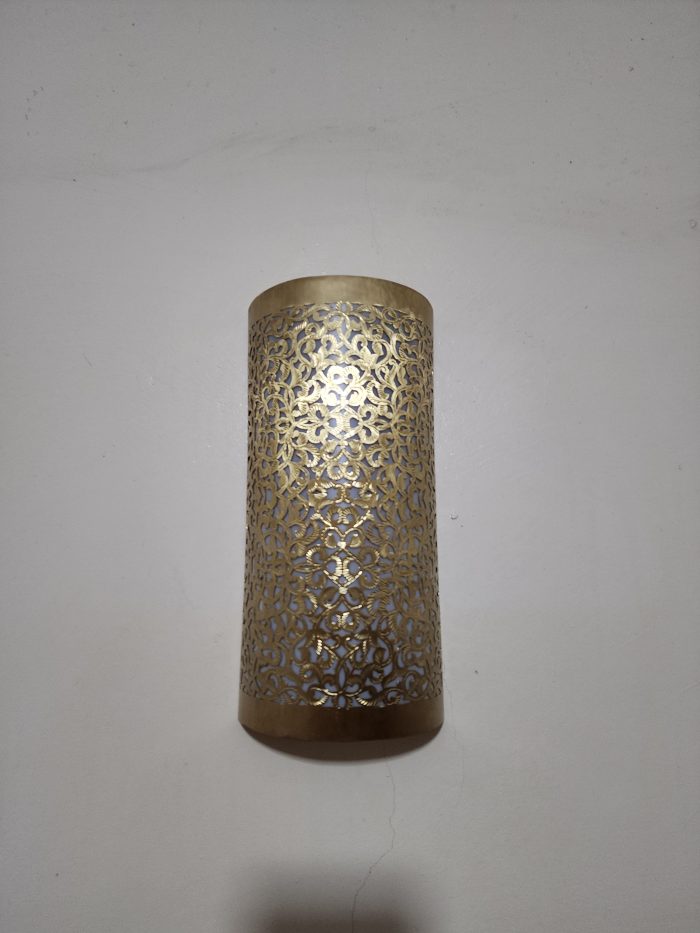 Handmade filigree brass wall sconce with intricate floral cutout pattern and warm ambient wall lighting.