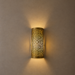 Handmade filigree brass wall sconce with intricate floral cutout pattern and warm ambient wall lighting.