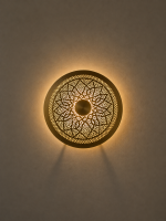 Handmade round brass wall light with floral rosette openwork, solid center medallion and warm glowing halo.