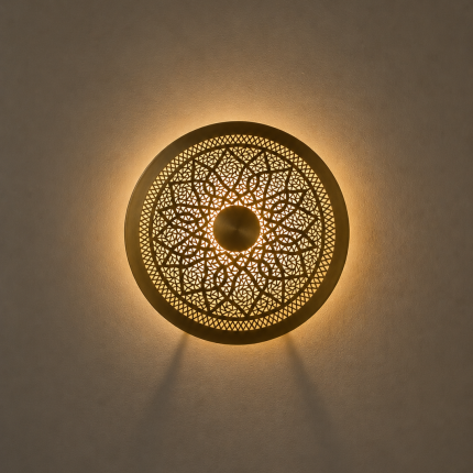 Handmade round brass wall light with floral rosette openwork, solid center medallion and warm glowing halo.