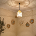 Handwoven raffia lantern pendant with tall tapered shape, natural woven raffia and structured metal frame.