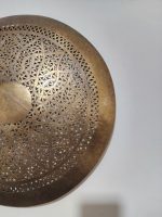 Handmade round brass wall light with floral rosette openwork, solid center medallion and warm glowing halo.
