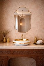 Handmade scalloped arch brass wall mirror with decorative gold frame above a bathroom vanity.