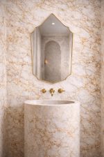 Handmade Moroccan pointed arch brass mirror with slim gold frame above a bathroom vanity.