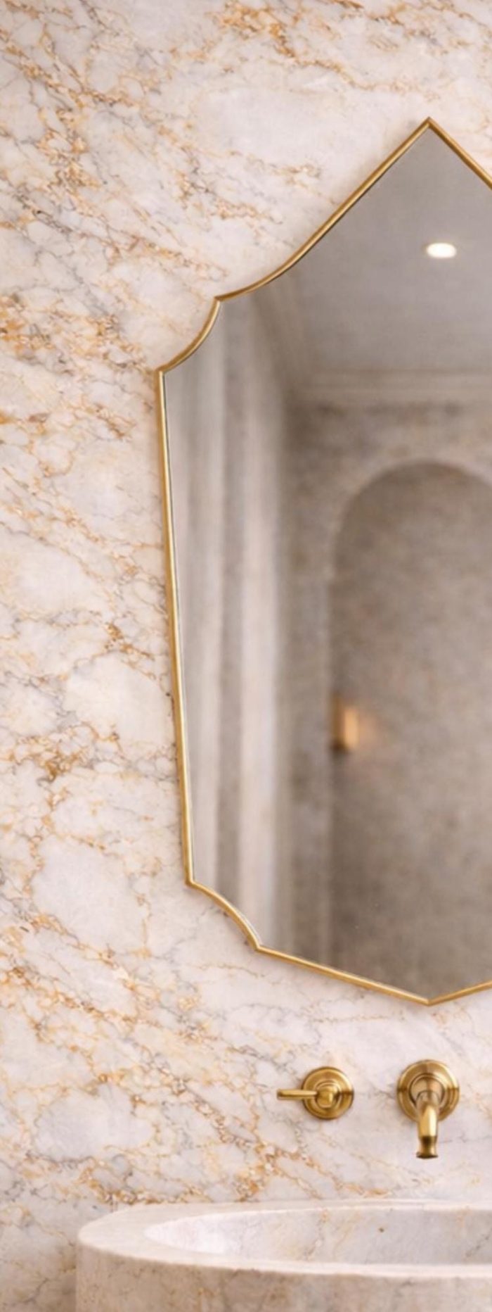Handmade Moroccan pointed arch brass mirror with slim gold frame above a bathroom vanity.