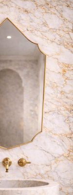 Handmade Moroccan pointed arch brass mirror with slim gold frame above a bathroom vanity.