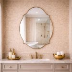 Handmade curved crown brass wall mirror with scalloped edges and solid brass frame above bathroom vanity.