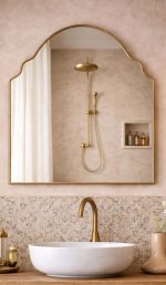 Handmade crown arch brass wall mirror with curved shoulders and slim gold brass frame above a bathroom vanity.