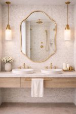Handmade sculpted oval brass wall mirror with flowing curved edges and solid brass frame above double bathroom vanity.