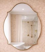 Handmade curved crown brass wall mirror with scalloped edges and solid brass frame above bathroom vanity.