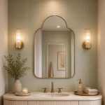 Handmade rounded crown brass wall mirror with clear glass and solid brass frame displayed above an elegant bathroom vanity.