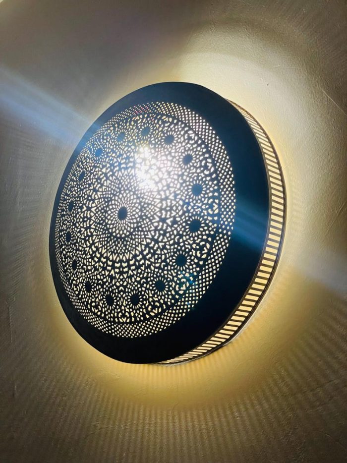 Handmade round brass wall light with intricate mandala pattern and radiant warm halo illumination.