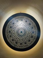 Handmade round brass wall light with intricate mandala pattern and radiant warm halo illumination.