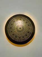 Handmade round brass wall light with intricate mandala pattern and radiant warm halo illumination.