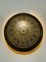 Handmade round brass wall light with intricate mandala pattern and radiant warm halo illumination.
