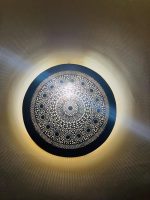 Handmade round brass wall light with intricate mandala pattern and radiant warm halo illumination.