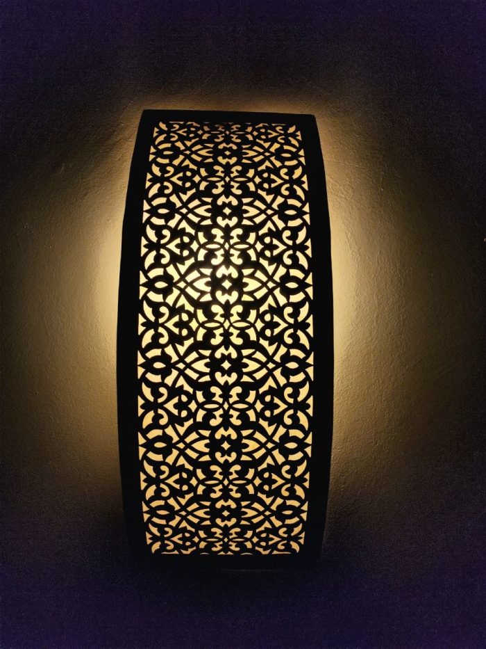 Handmade lattice filigree brass wall sconce with bowed rectangular shape, ornamental openwork and warm ambient lighting.