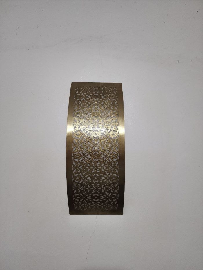 Handmade lattice filigree brass wall sconce with bowed rectangular shape, ornamental openwork and warm ambient lighting.