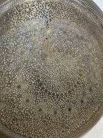 Handmade Moroccan brass wall light with round pierced floral design and warm halo illumination.