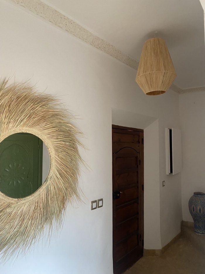 Handwoven palm leaf mirror with round glass center and natural sunburst fringe wall decor